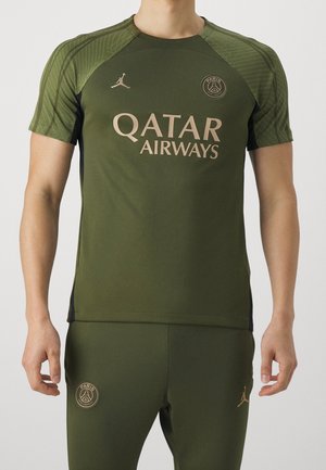 Mand iført olivengrønt Paris Saint-Germain træningstøj med Qatar Airways-logo og Jordan-mærke.