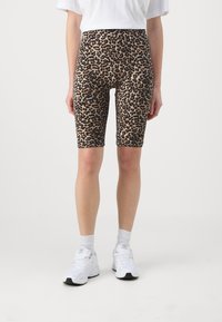 Pantaloni bike a stampa leopardata in un tessuto elasticizzato e morbido, con vita alta e silouette aderente, abbinati a sneaker bianche e calze.