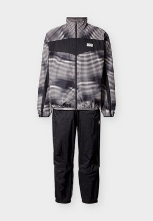 Dvojdielna športová súprava čiernej a sivej farby s pruhovanou bundou, predným zipsom, elastickými manžetami a čiernymi nohavicami s elastickými členkami.