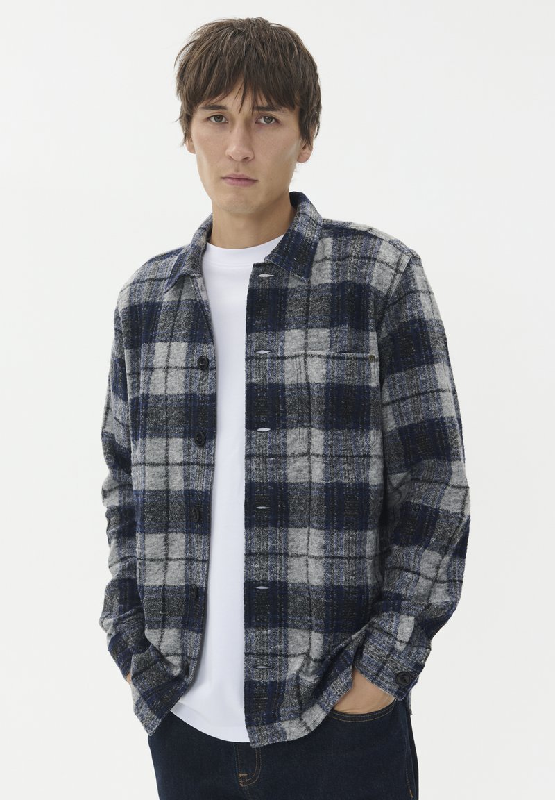 Flanelasta srajca z vzorcem v sivo, mornarsko modri in modri barvi, z gumbom na sprednji strani, dolgimi rokavi in žepom na prsih.