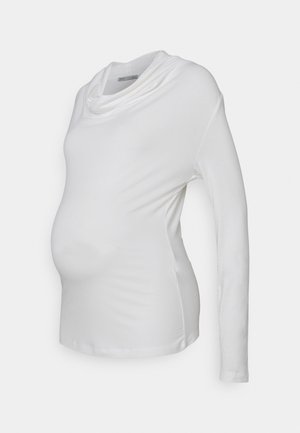 Fehér, hosszú ujjú kismama felső, lágy, rugalmas anyagból készült, cseppnyakú kialakítással; a testhez simuló dizájn kiemeli a várandós pocakot.