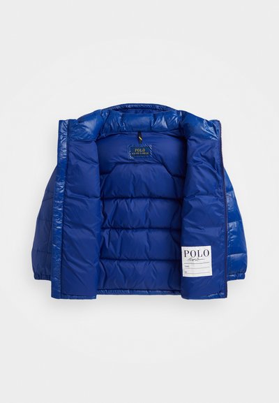Blå polstret jakke med en blank ytterstoff, horisontalt quiltet design og en etikett med "POLO" på venstre side.