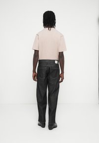 T-shirt rosa chiaro a maniche corte abbinata a jeans in denim scuro. I jeans presentano un leggero effetto consumato e tasche posteriori classiche.