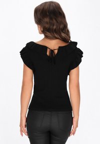 Top negru cu nervuri, cu un decolteu larg cu volane și mâneci scurte, având un sistem de închidere legat la spate. Textură netedă și design ajustat.