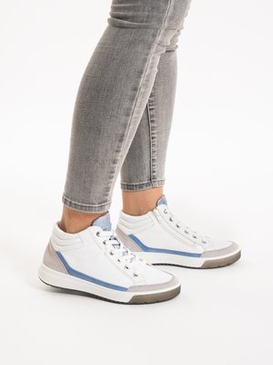 Person wearing gray jeans and white high-top sneakers with blue and gray accents, standing on a white background.