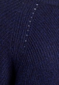 Jersey de punto azul marino con un patrón texturizado, que presenta un ligero acanalado y pequeños agujeros a lo largo de la costura para añadir detalle visual.