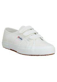 Chaussure en toile de coton blanc avec des sangles à scratch, semelle en caoutchouc, talon texturé et motif en losange sur le capuchon des orteils. Logo rouge et bleu.