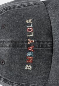 Gorra de béisbol gris con bordado multicolor. El diseño incluye una tela texturizada con visera curva y construcción de seis paneles.