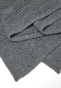 Couverture en tricot douce de couleur grise avec des motifs texturés et des éclats subtils. Présente des designs en torsade et en dentelle, offrant chaleur et confort.