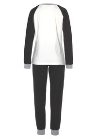 Black and white cotton pajama set featuring a long-sleeve, raglan-style top with contrasting sleeves and fitted, cuffed pants.