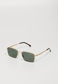 Occhiali da sole in metallo color oro con lenti verdi, forma squadrata, aste sottili e punte nere. Presentano soft pad nasali trasparenti per il comfort.