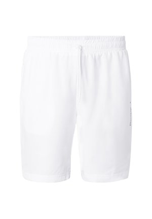 Hvide shorts med elastik i taljen, snøre og diskret tekstdetalje på højre lår, vist mod en ensfarvet baggrund.