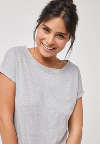 Chemise courte à manches courtes gris clair avec un col en bateau. Tissu doux et texturé. Coupe confortable avec des manches roulées, idéale pour un style décontracté.