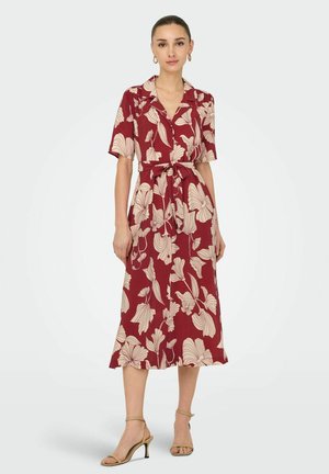 Maxi dress in deep red with cream floral patterns, short sleeves, collared design, button front, and a tied waist. Features a flowing silhouette.