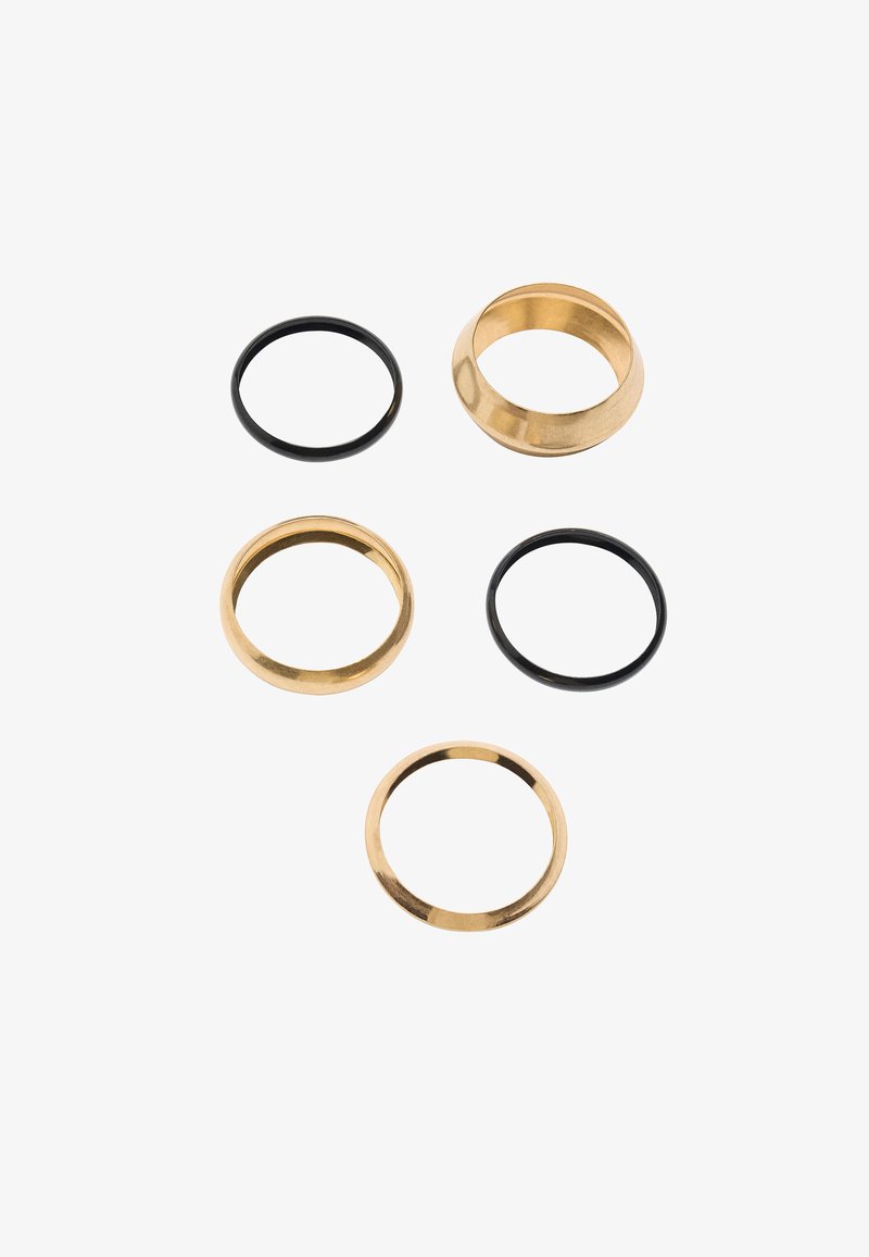 Zestaw pięciu pierścionków, w tym trzy złote pierścionki metalowe i dwa czarne pierścionki gumowe. Złote pierścionki mają gładkie wykończenie oraz różne kształty.