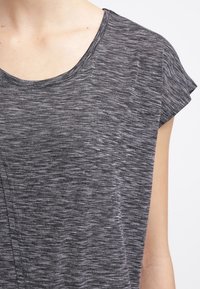 Top grigio a maniche corte realizzato in un tessuto texturizzato con effetto mélange, dotato di un collo ampio e con delicate cuciture decorative sul davanti.