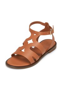 Brown leather sandal featuring cut-out star shapes, ankle strap with buckle, flat sole, and a smooth texture.