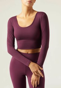 Burgunderfarbenes Langarm-Crop-Top mit Rundhalsausschnitt und enganliegendem Schnitt, kombiniert mit passenden hochtaillierten Leggings aus dehnbarem Stoff.