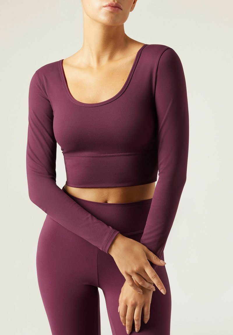 Burgunderfarbenes Langarm-Crop-Top mit Rundhalsausschnitt und enganliegendem Schnitt, kombiniert mit passenden hochtaillierten Leggings aus dehnbarem Stoff.