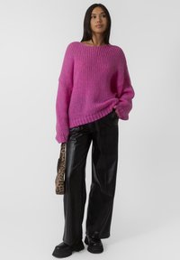 Maglione rosa a maglia con vestibilità comoda, texture a coste e maniche ampie, abbinato a pantaloni in ecopelle neri e una borsa con stampa leopardata.