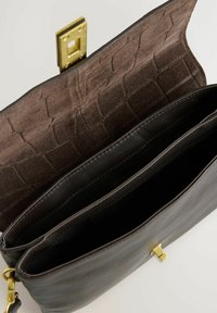 Sort læderhandtaske indvendigt med en brun ruskindsforing med krokodilleskindsstruktur. Den har to rum og en guldhardware-lås.