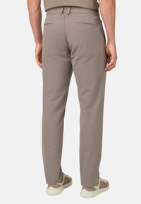 Pantaloni slouch leggeri marrone chiaro da uomo con una vestibilità slim, dotati di due tasche posteriori e una texture liscia, abbinati a sneaker beige.