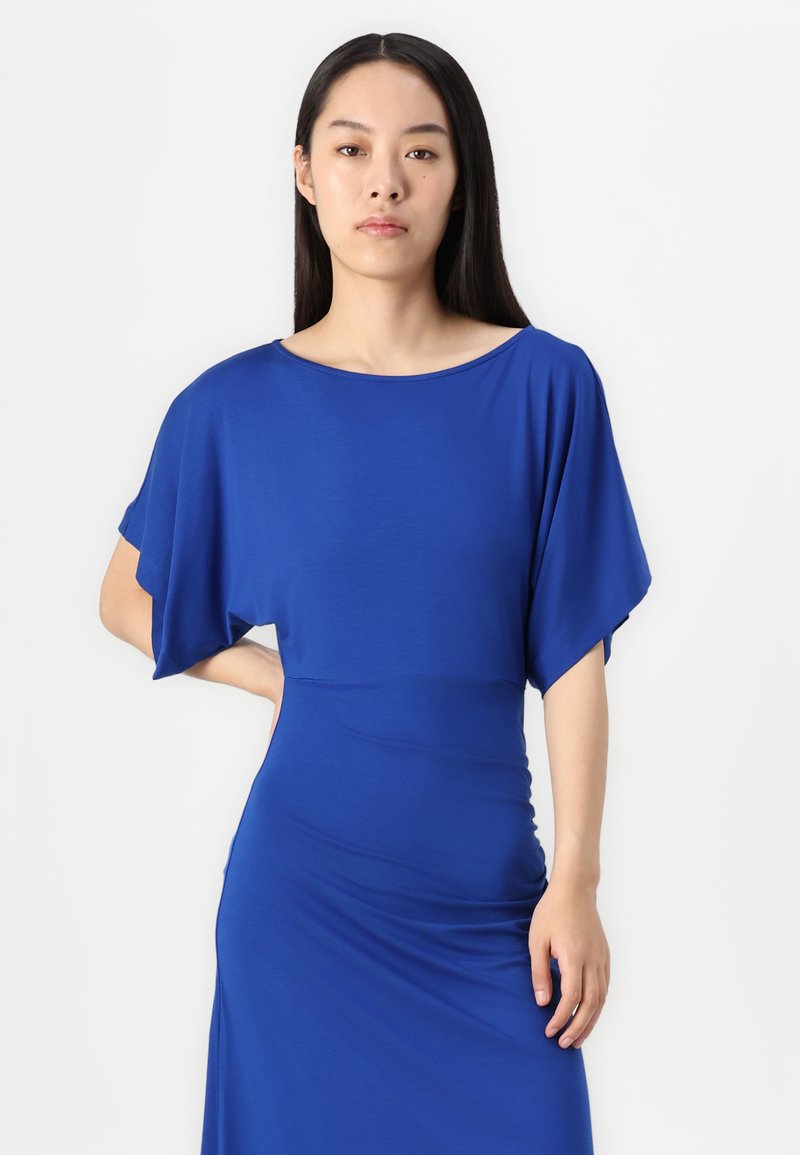 Blaues Kleid aus glattem Stoff mit weitem Bootsausschnitt und lockeren Ärmeln, das eine figurbetonte Silhouette hat und bis zu den Knöcheln reicht.