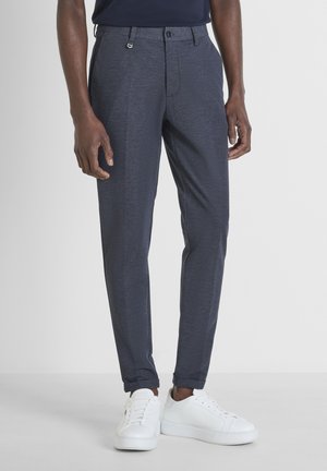 Pantalones de marinero con un acabado texturizado, corte recto y presillas para el cinturón, combinados con zapatillas blancas. Presenta un cierre de botón único y bolsillos frontales.