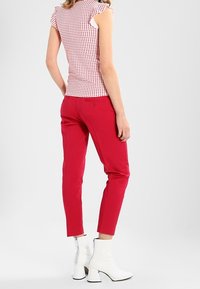 Fitted red pants paired with a white and red polka dot top. The top features cap sleeves. White ankle boots complete the look.