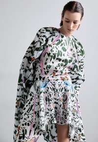 Robe à motif floral en tissu léger. Présente des designs verts, roses et bleus, des manches longues et un ourlet fluide.