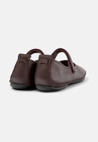 Brown leather shoes with elastic loops, soft texture, rounded shape, featuring a black rubber sole and embossed logo at the heel.