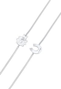 Silverhalsband med en texturerad oregelbunden hänge och en polerad hängande hästskoformad charm. Varje komponent är kopplad med en delikat kedja.