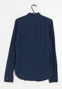 Tummansininen pitkähihaine paita, joka on valmistettu sileästä kankaasta. Paidassa on nappikaulus, kaareva helma ja napilliset hihansuut, joissa on logoyksityiskohta.