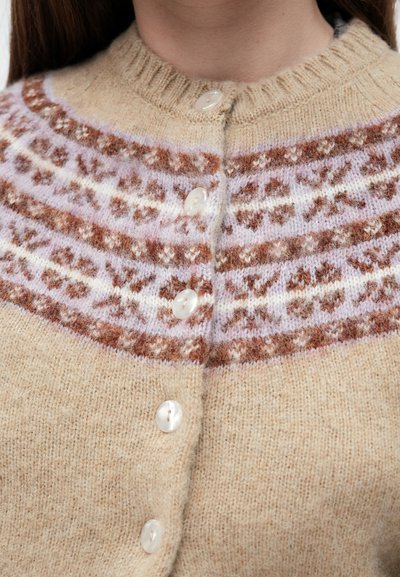 Μπεζ πλεκτή ζακέτα με σχέδιο fair isle σε καφέ, ροζ και λευκό. Διαθέτει ριμπ γιακά και πέντε κουμπιά μπροστά.