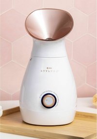 Vit ansiktsångare med en metallisk roséguld konformad topp, roterande ratt i botten och en slät, rundad design.