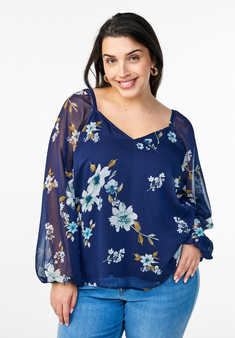 Blusa navy con motivo floreale, realizzata in tessuto leggero. Presenta un collo a V e maniche lunghe trasparenti con polsini elasticizzati.