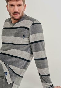 Camisa de manga larga a rayas grises con líneas horizontales negras, con un bolsillo en el pecho, textura suave y diseño de escote en V.