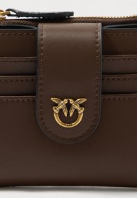 Brown leather wallet featuring a gold emblem with two birds, a snap closure, multiple card slots, and textured stitching details.
