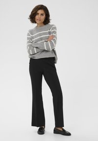 Gray sweater with white stripes, ribbed texture, paired with black flared pants, featuring side buttons and a smooth finish, worn with black loafers.