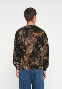Fleece sweatshirt met een multicolore, abstracte bladenpatroon in aardetinten. Heeft een ronde halslijn en ribgebreide manchetten.