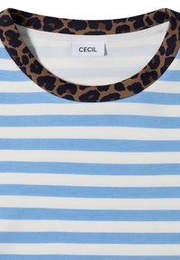 Chemise rayée bleue et blanche avec un col rond ornée d'une bordure imprimé léopard marron et noir et d'une étiquette blanche avec le texte "CECIL".