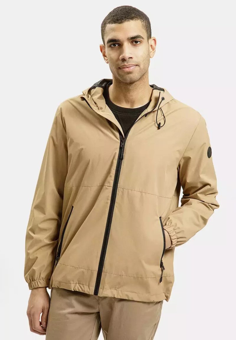 Lekka beżowa kurtka z zamkiem z przodu, regulowanym kapturem, elastycznymi mankietami i bocznymi kieszeniami, wykonana z tkaniny wodoodpornej.