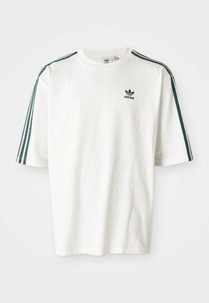 Weißes Baumwoll-T-Shirt mit kurzen Ärmeln, das dunkle grüne Streifen an den Schultern und ein kleines schwarzes Adidas-Logo auf der Brust hat.