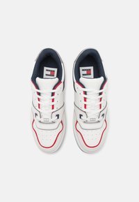 Zapatillas blancas con acentos rojos y azules, parte superior de cuero texturizado, punta redonda, cuello acolchado y diseño de cordones. Logo en la lengüeta.