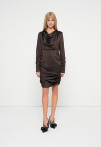 Rochie din satin, maro închis, cu mâneci lungi, decolteu tip cowl, cu drapaje laterale, de lungime medie, asociată cu pantofi cu toc black slingback, având accente cu fundițe.