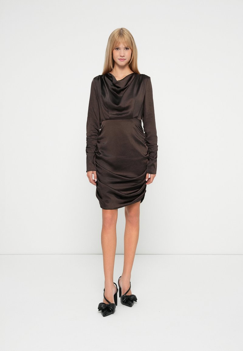 Rochie din satin, maro închis, cu mâneci lungi, decolteu tip cowl, cu drapaje laterale, de lungime medie, asociată cu pantofi cu toc black slingback, având accente cu fundițe.