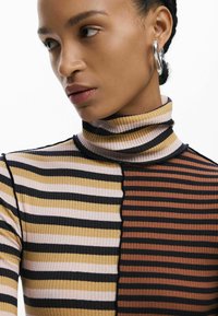 Gestreiftes Rollkragenoberteil mit gerippter Textur, das abwechselnd in Braun-, Schwarz- und gedeckten Pastellfarben gehalten ist. Enganliegendes Design mit hohem Kragen.