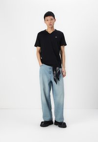 Musthave mustaga, lahtine heledad sinised teksad, mille vöös on must-valge bandaan, ning paksud mustad jalanõud. Minimalistlik disain.