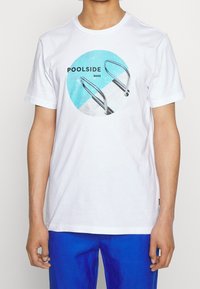 Bílý bavlněný tričko s kulatým grafickým motivem, na kterém je modrá bazénová voda a kovový žebřík do bazénu. Na tričku je nápis "POOLSIDE BOSS."