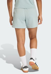 Lichtblauwe, gestructureerde shorts met een aansluitend ontwerp, gecombineerd met witte sokken en zwarte sportschoenen. Ansicht van de achterkant.